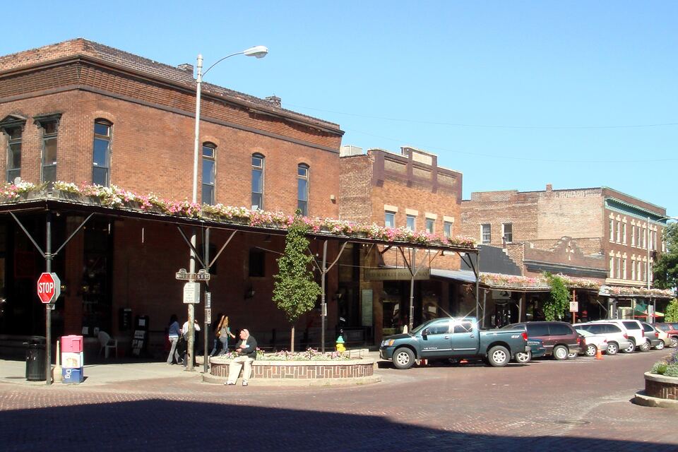 Brick warehouse buildings with a covered sidewalk canopy on a brick-paved street corner in Omaha's Old Market.